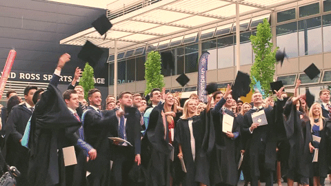 A group of university students throwing their graduation caps into the air.